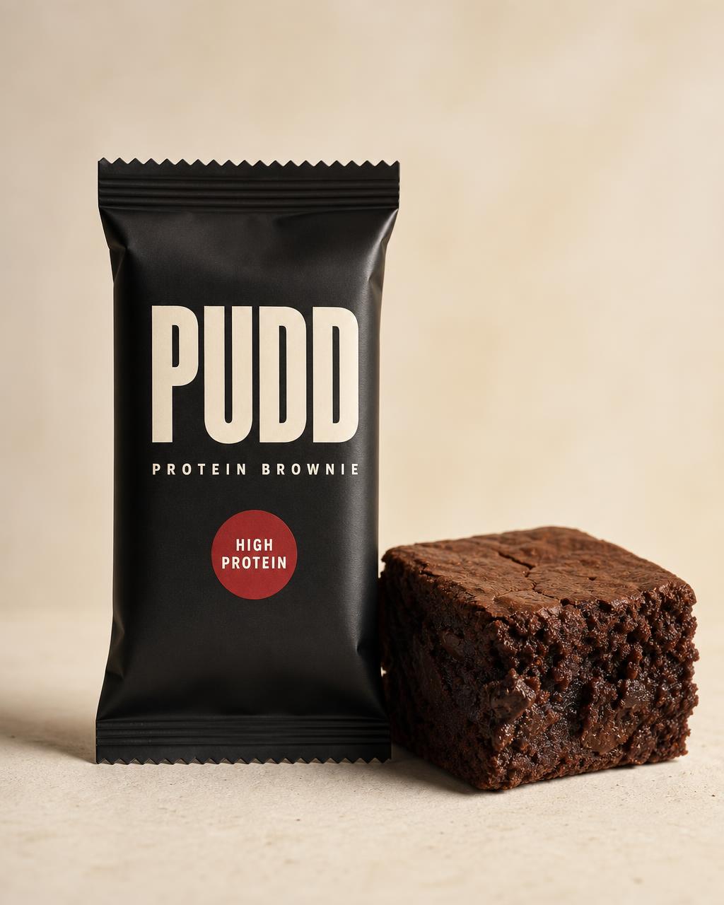 PUDD Protein Brownies concept packaging in matte black with cream PUDD wordmark